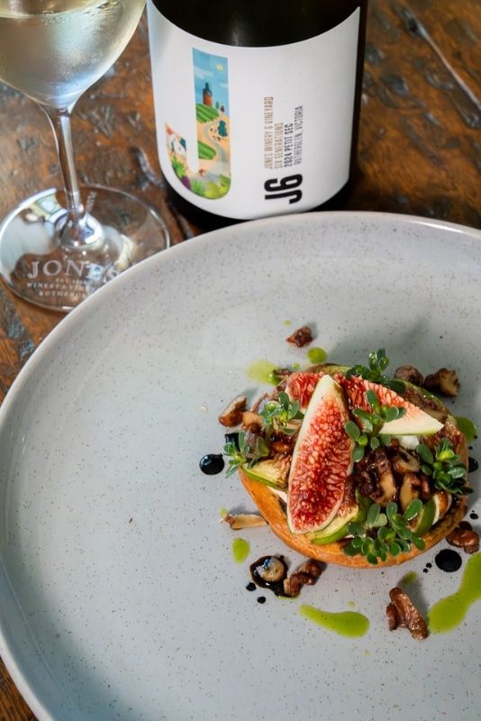 Seasonal dish served at Jones Winery Restaurant in Rutherglen, Victoria, paired with a glass of wine and a bottle of J6 wine on a rustic timber table.